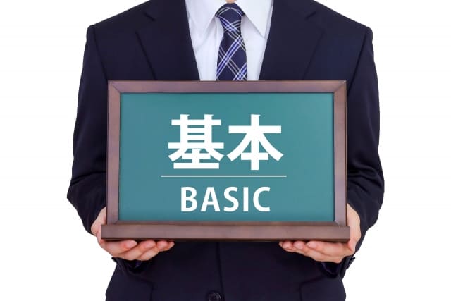 「基本」と書かれたミニ黒板を持つ男性