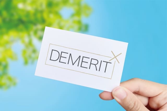 「DEMERIT」と書かれたカードを持つ手
